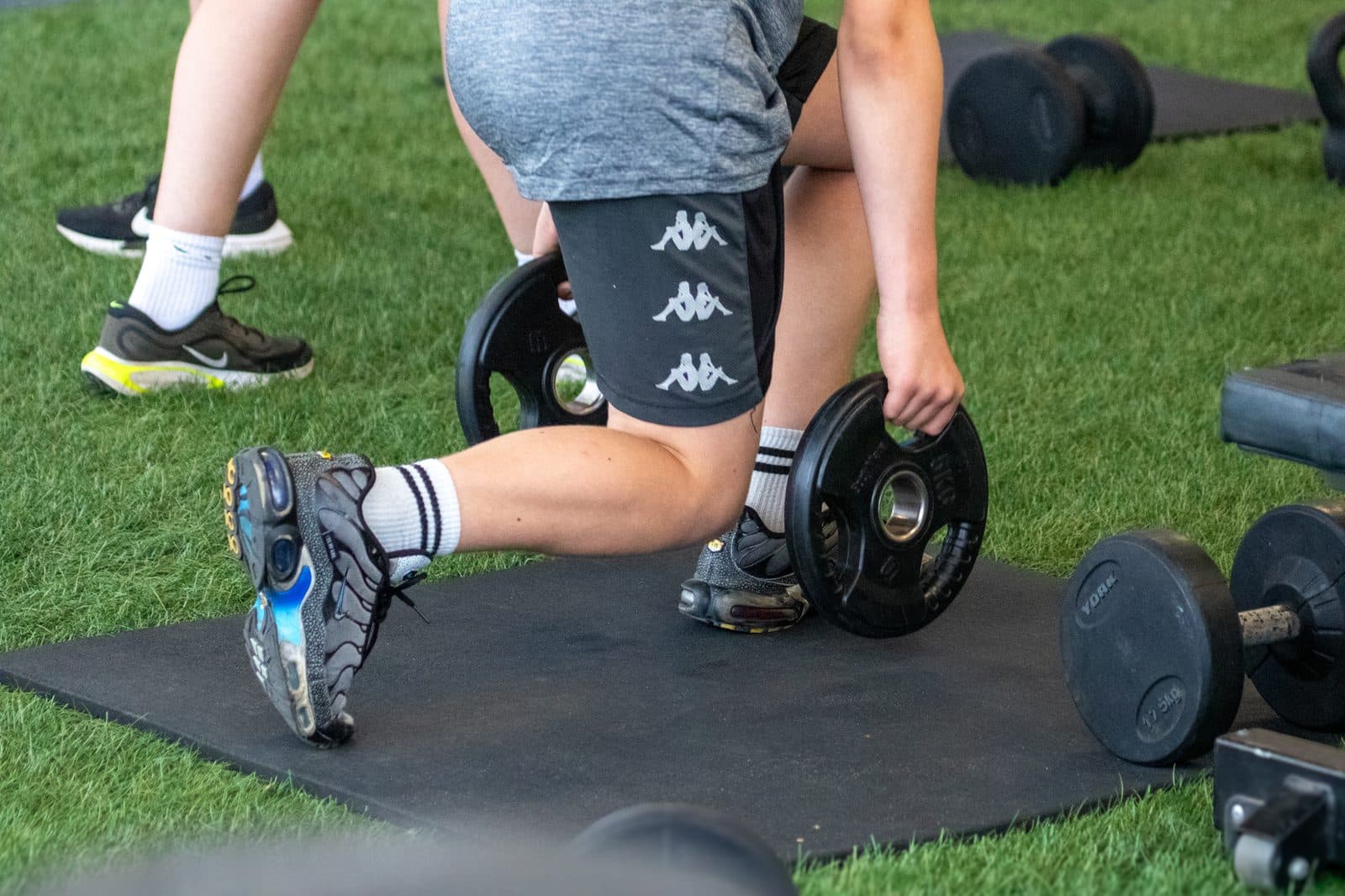 A young athlete working through a loaded lunge on the grass